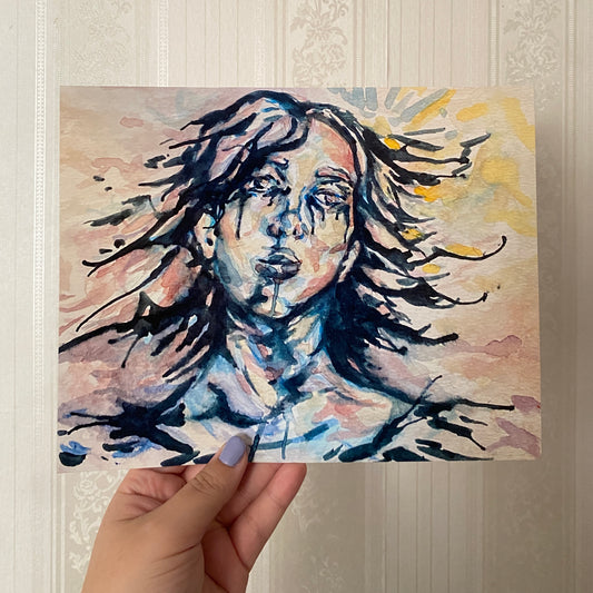 Hand holding a painting of a woman with flowing hair against a textured wall.